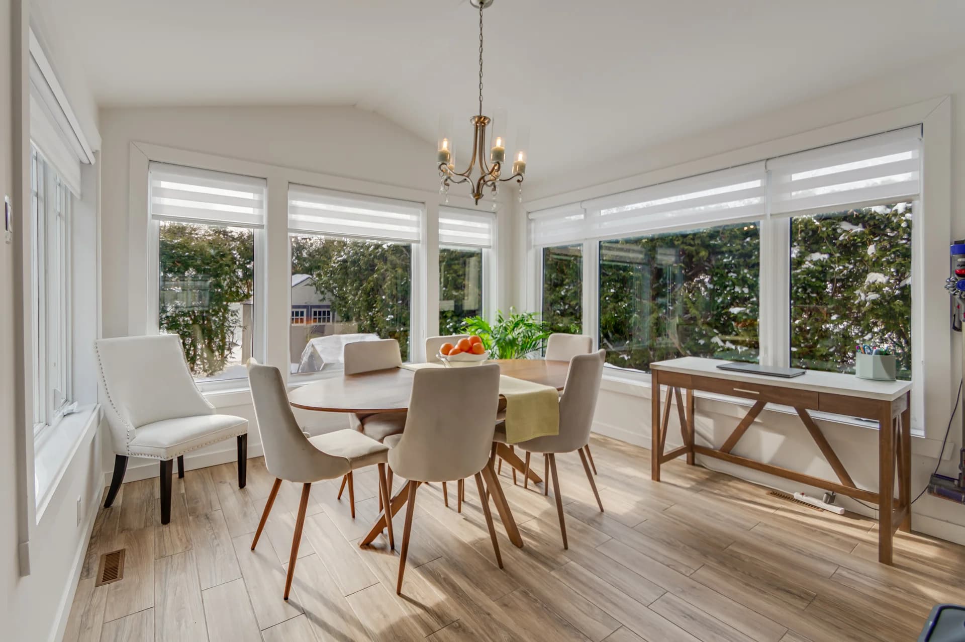 Coin repas vitré avec chaises blanches et console en bois