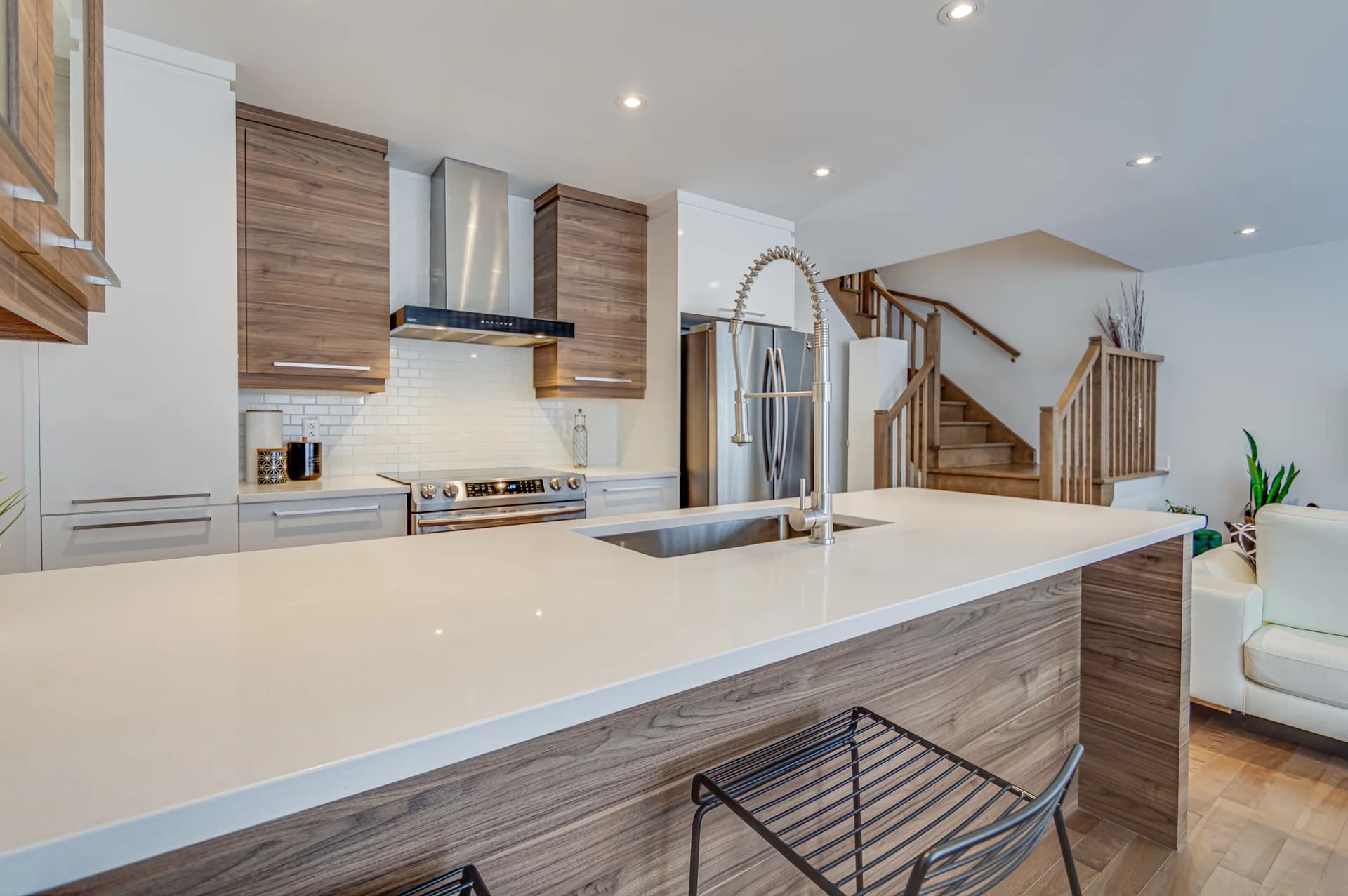 Îlot de cuisine blanc devant un escalier et des armoires en bois