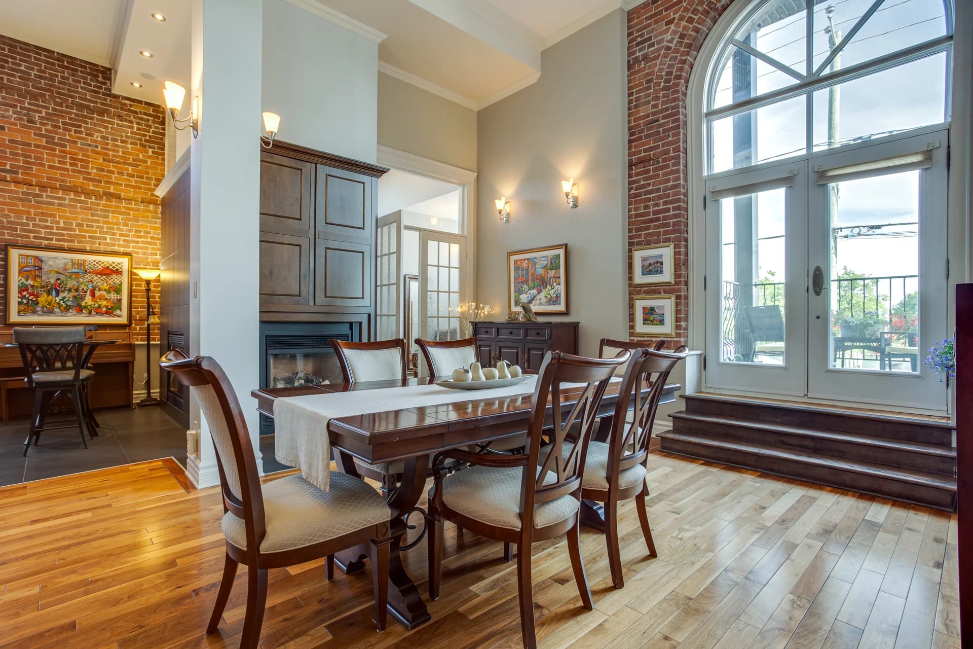Salle à manger avec mur de brique et grande fenêtre cintrée