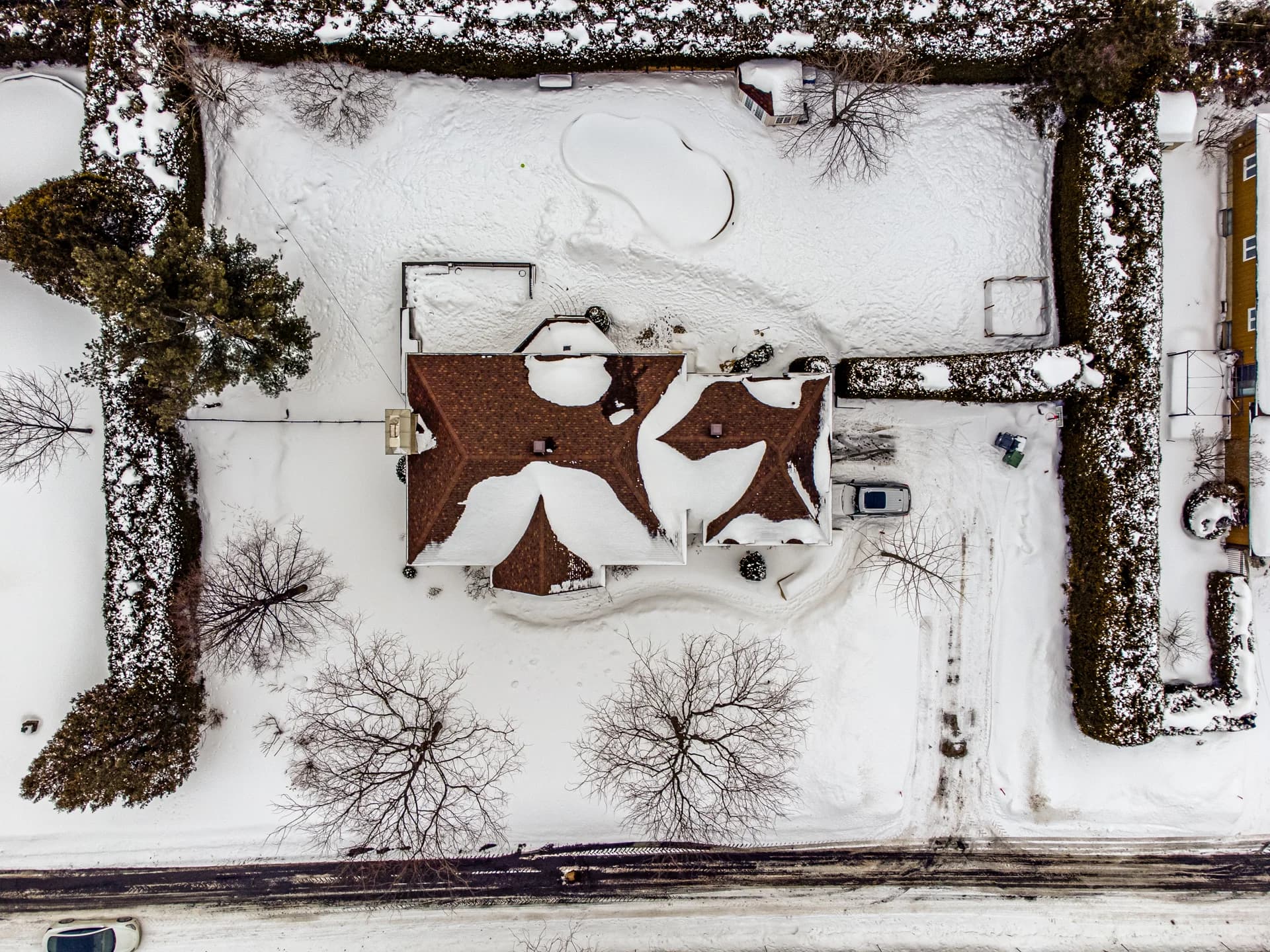 Vue de drone verticale d'une maison et de son terrain enneigé
