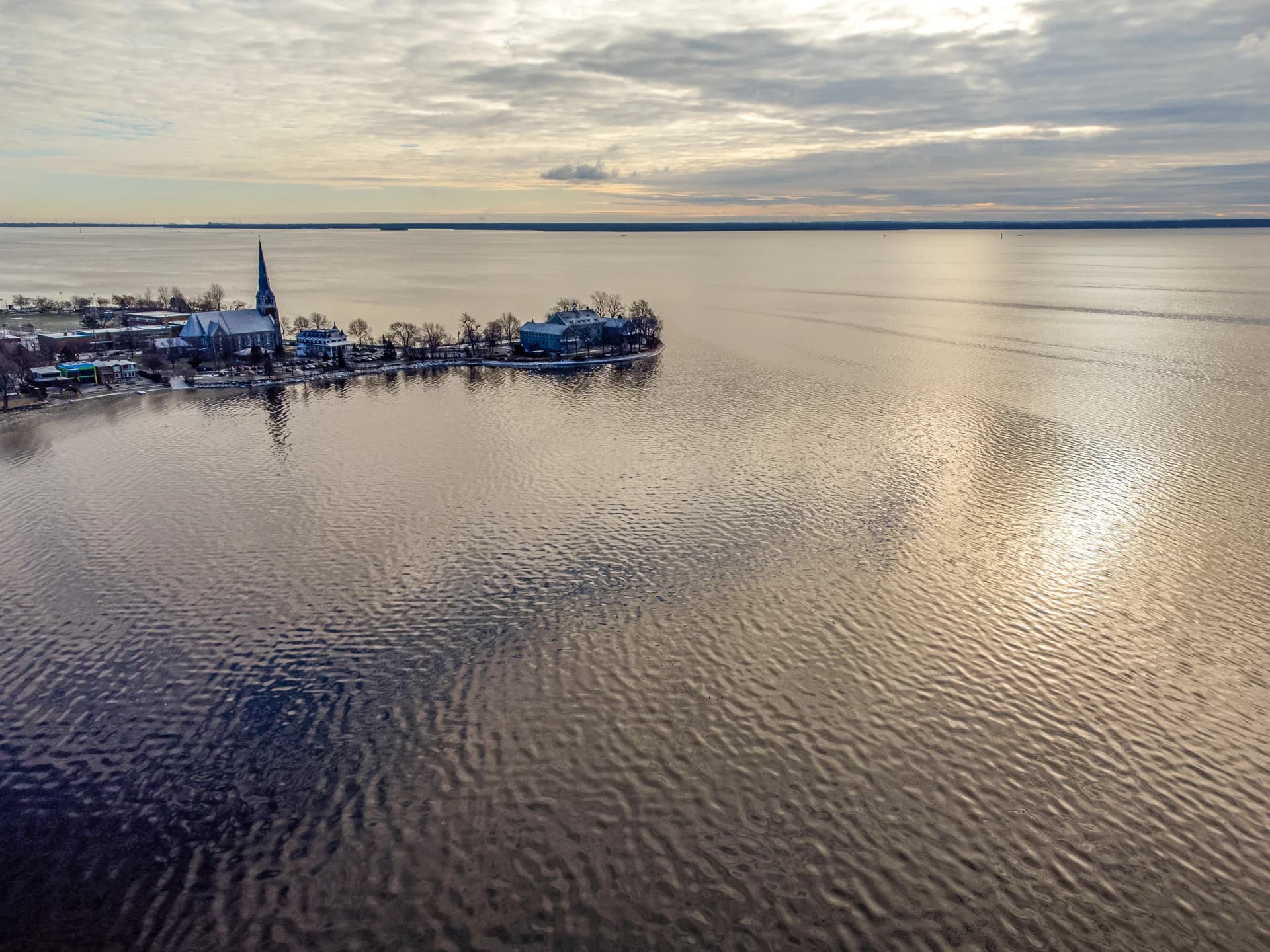 Vue de drone sur le bord de l'eau et une église au soleil bas